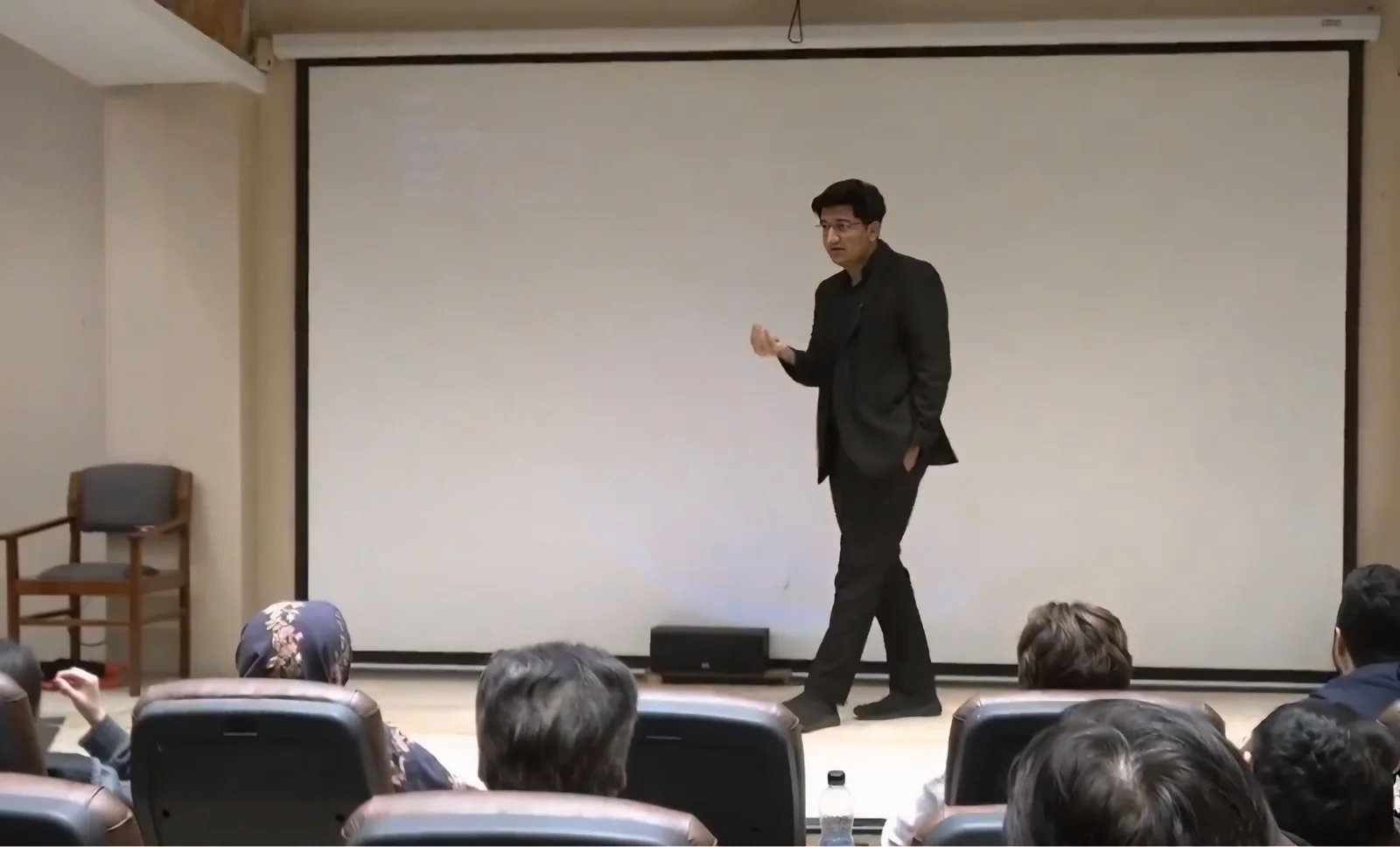 Salman Ahmad Awan speaking to an audience in an auditorium