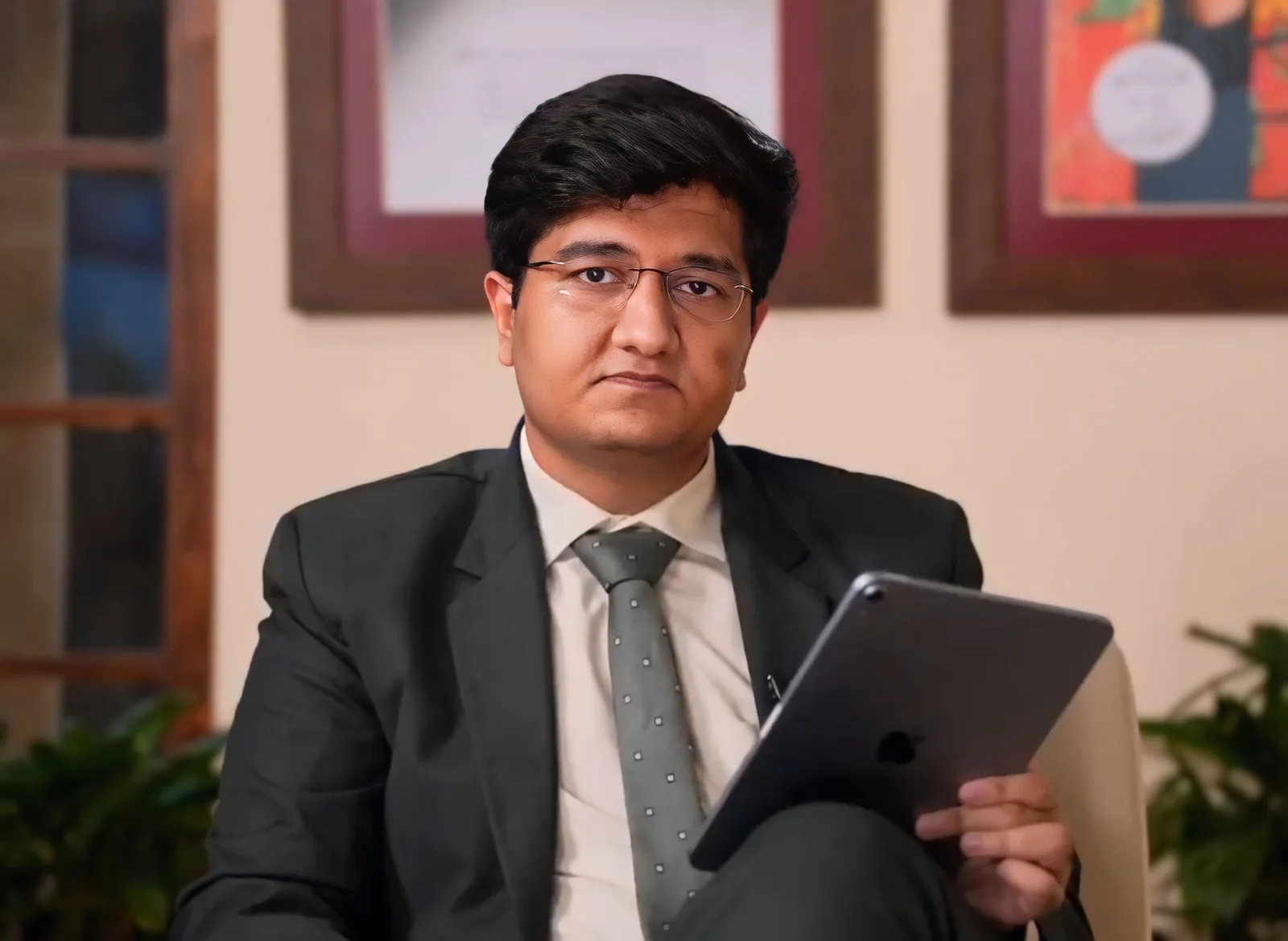 Salman Ahmad Awan seated in a suit holding a tablet